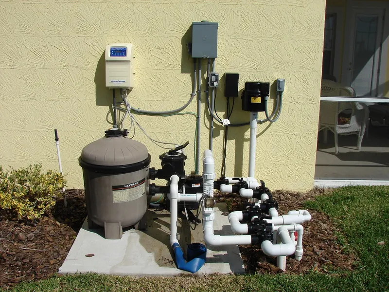 Residential pool pump, sand filter, and plumbing on an equipment pad