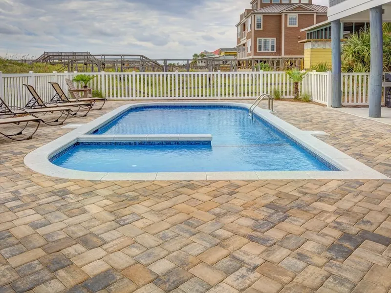 Clean rectangular pool with a paver deck and lounge chairs in San Marcos